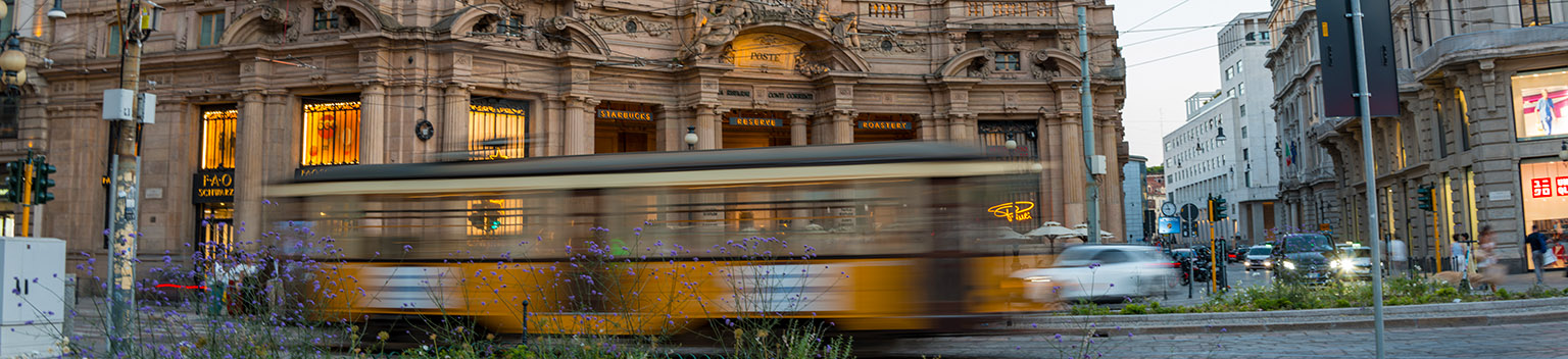 Panorama della tecnologia e del contesto degli investimenti in Italia: un'ampia veduta di una strada di Milano con vivaci visualizzazioni digitali di dati e grafici sulla crescita.